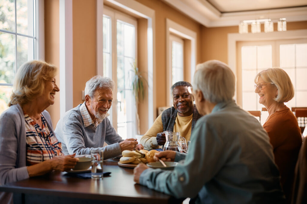 residents smiling around table enjoying a meal together