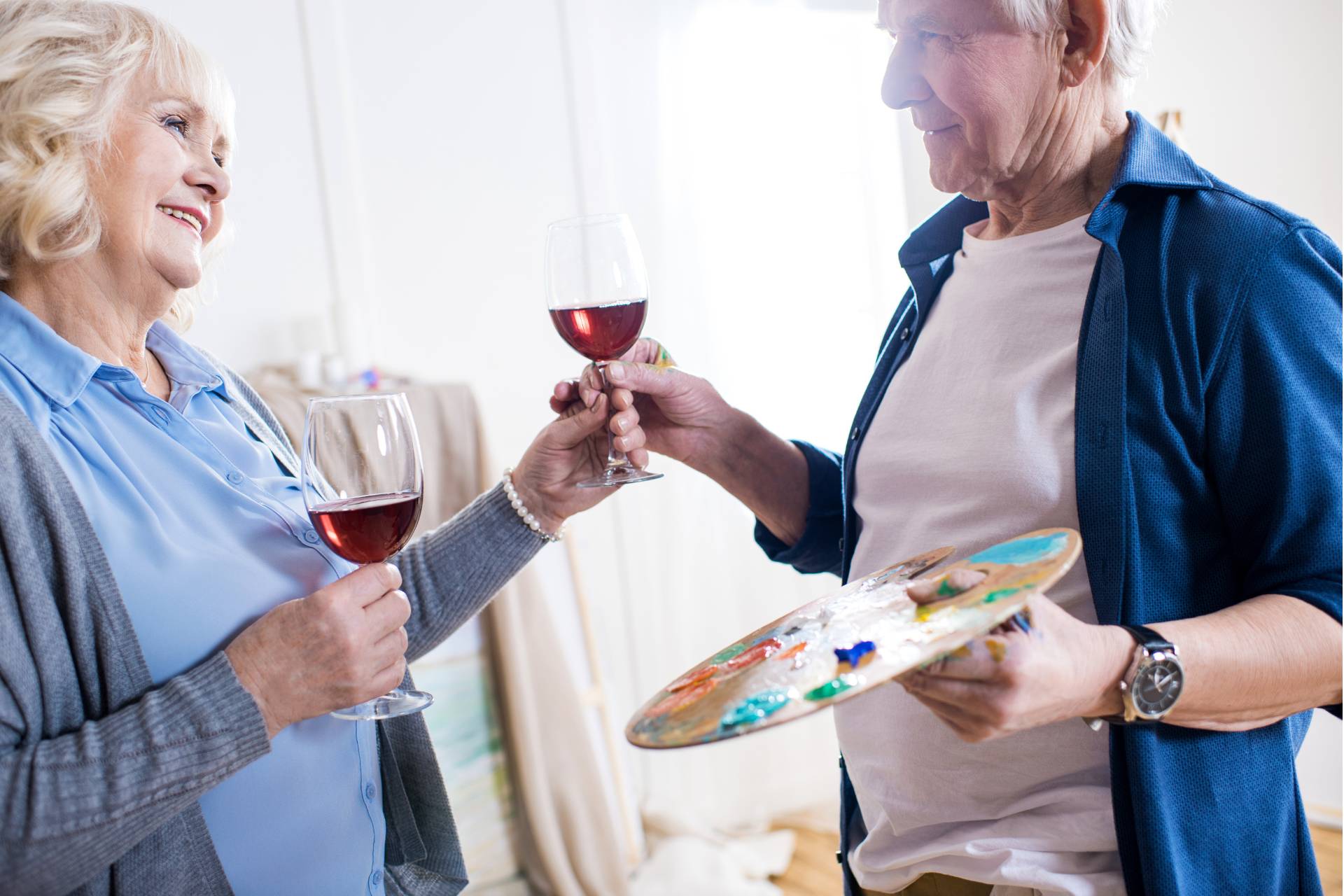 Senior Couple smiling together with wine and a paint palate