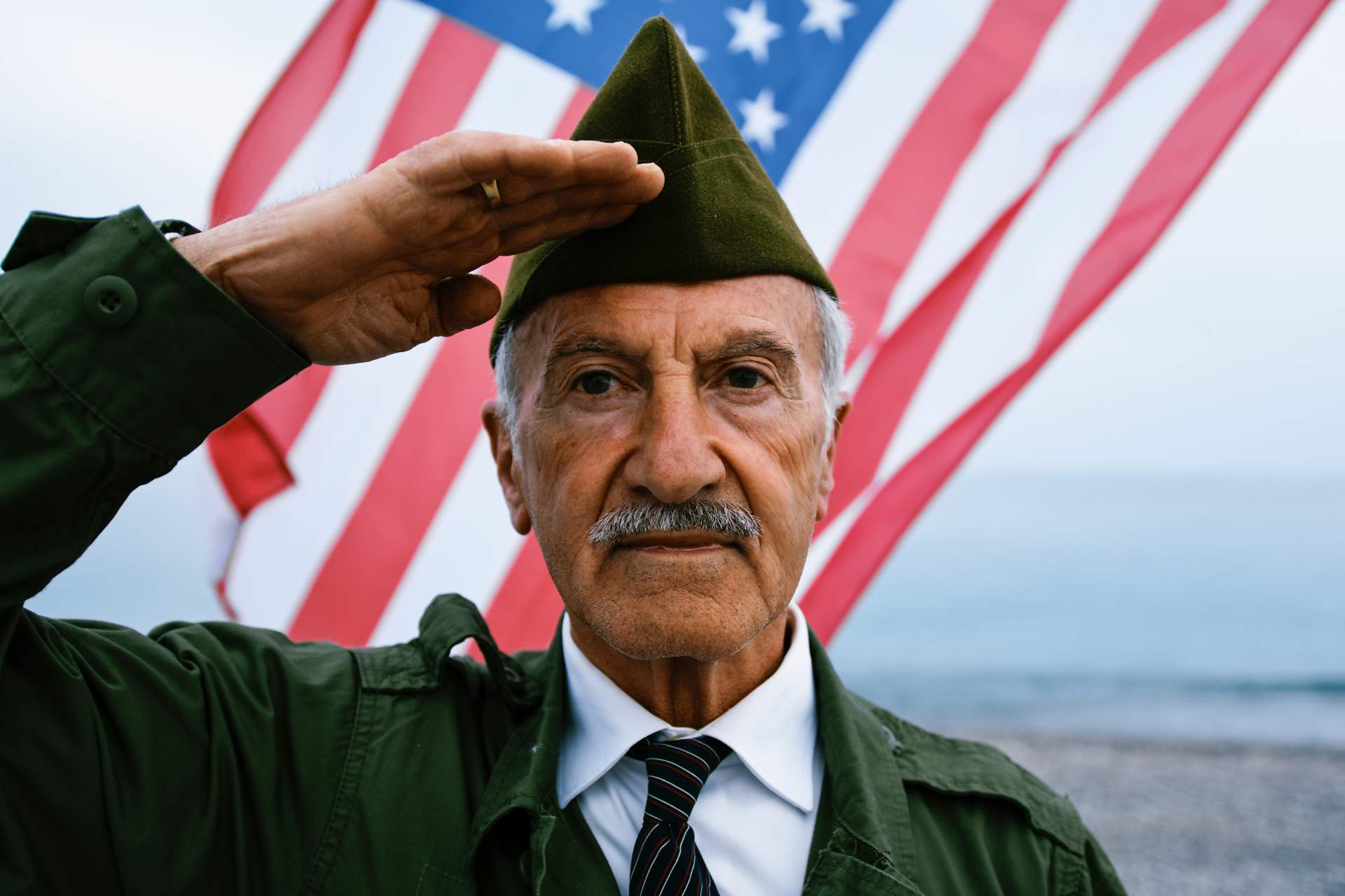 senior man wearing a veterans uniform in front of an American flag